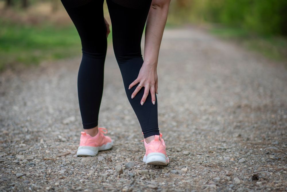 Läuferin hält sich schmerzend die Wade beim Sport im Freien – Symptom, das in der Sprechstunde für Innere Medizin in Münster abgeklärt werden kann